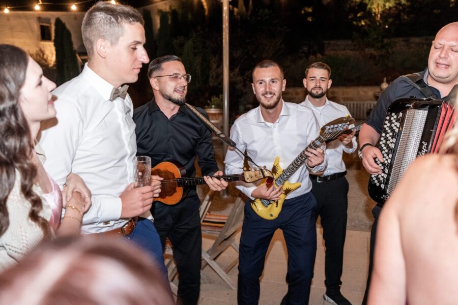 Hochzeitsgäste musizieren fröhlich mit Instrumenten.