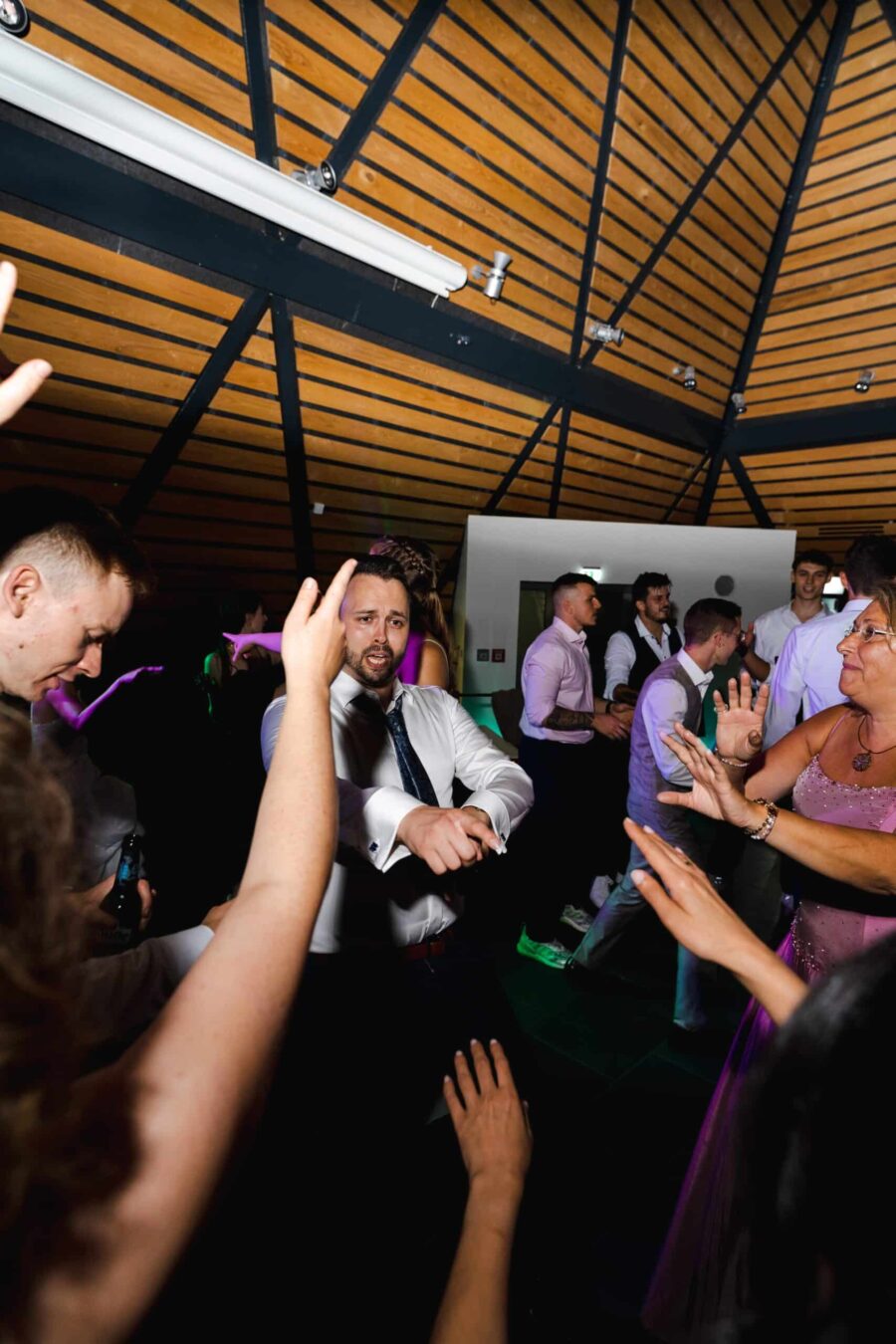 Hochzeitsgäste tanzen in festlichem Saal.