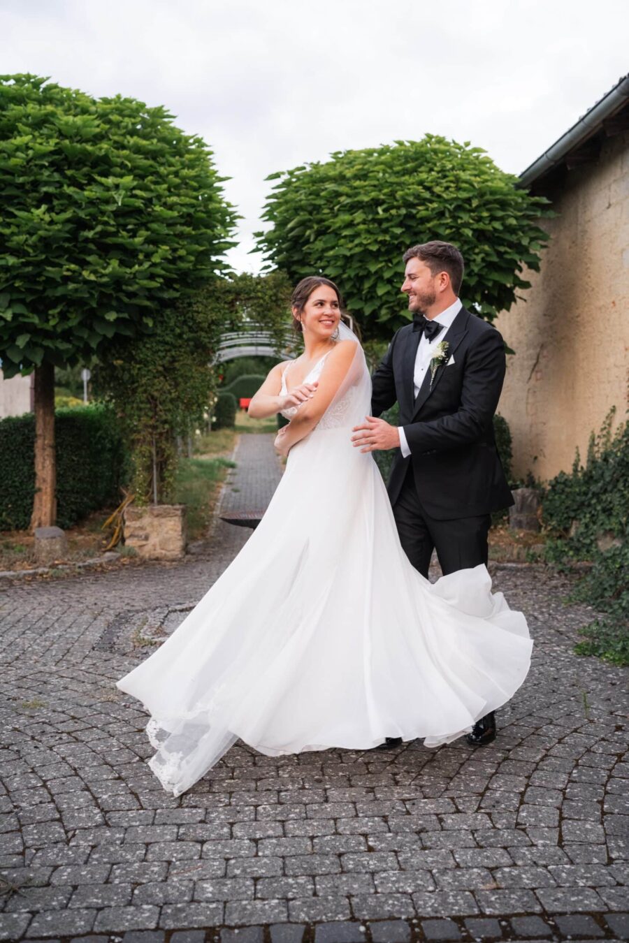 Brautpaar tanzt im Garten vor grünen Bäumen