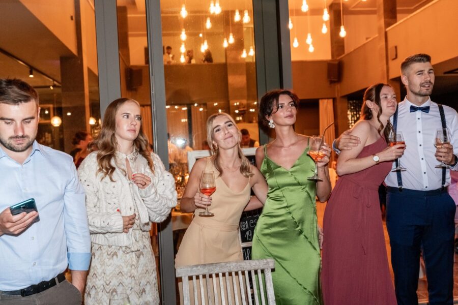 Gäste lachen und trinken bei Hochzeitsfeier im Saal.