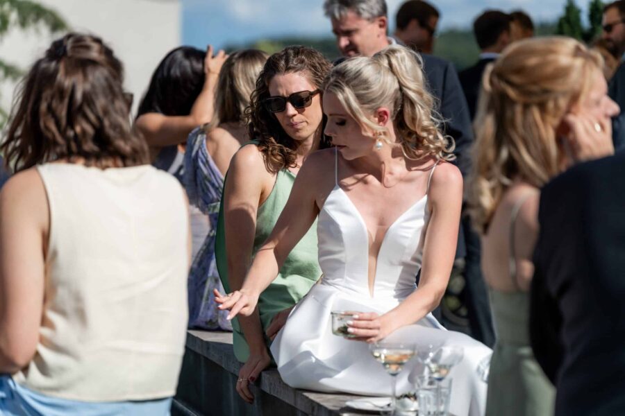 Hochzeitsgäste sitzen draußen, Sommerkleider, festliche Stimmung.