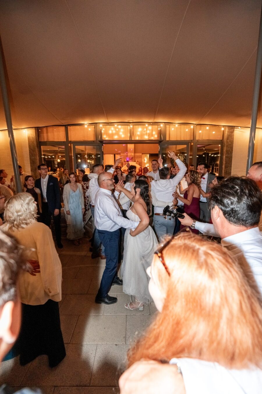 Hochzeitstanz mit Gästen in festlich beleuchtetem Saal