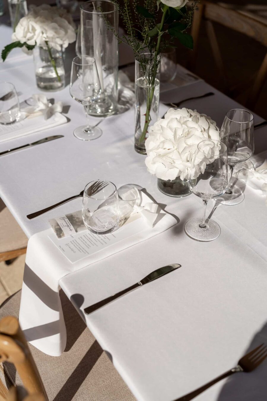 Weiß gedeckte Hochzeitstafel mit Blumenarrangement