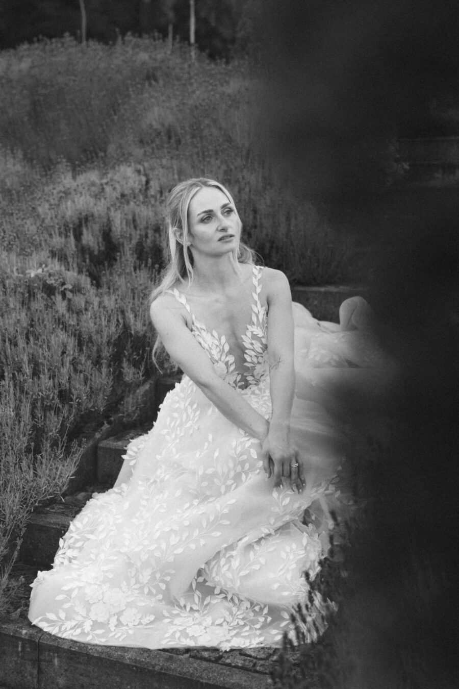 Braut im weißen Kleid auf Natursteintreppe