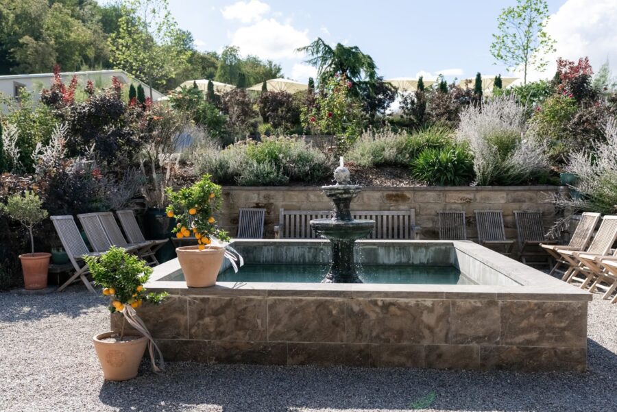 Garten mit Springbrunnen und Sitzgelegenheiten bei Sonnenschein