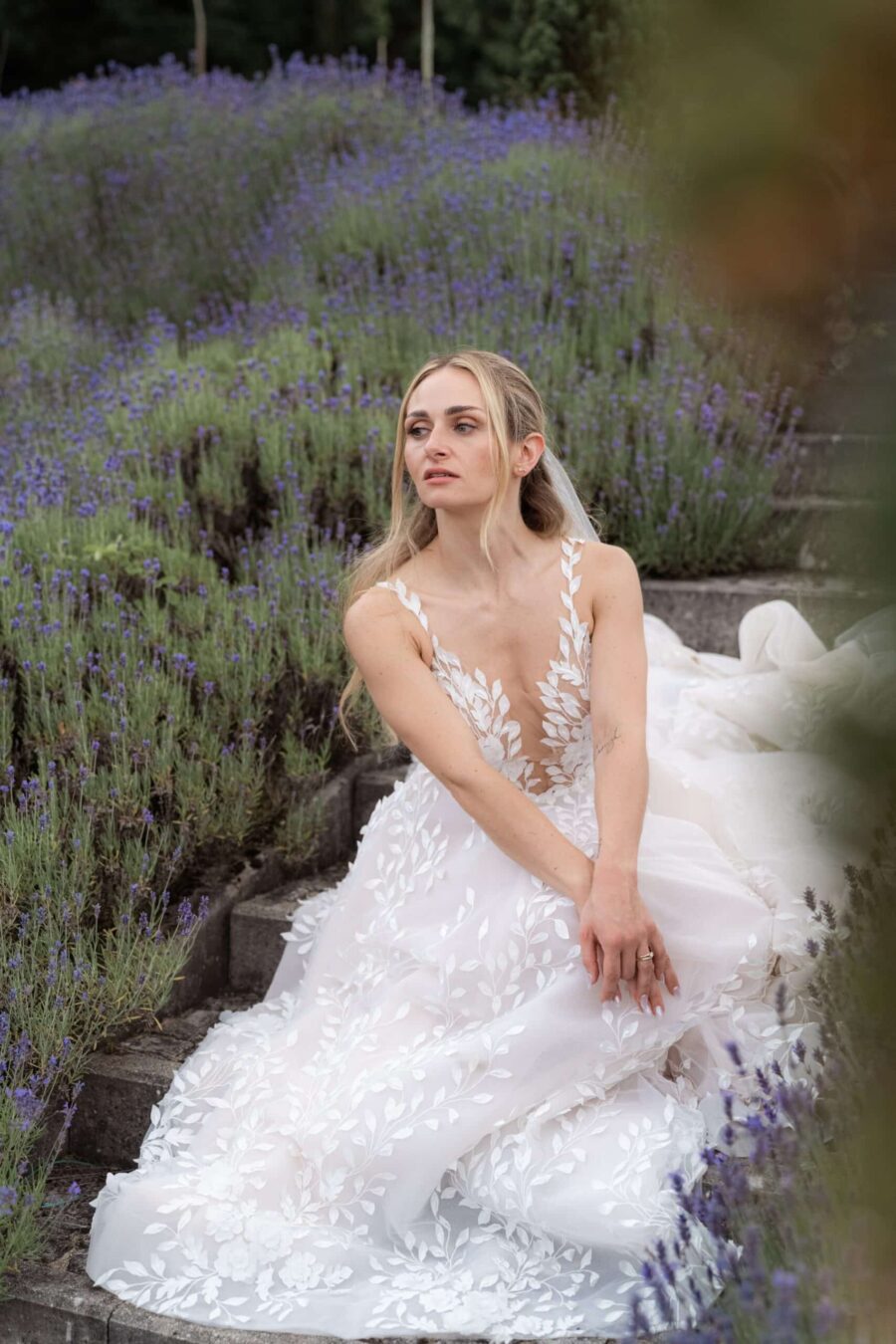 Braut im weißen Kleid sitzt im Lavendelgarten