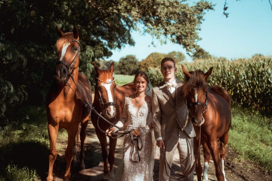Brautpaar mit Pferden im sonnigen Garten