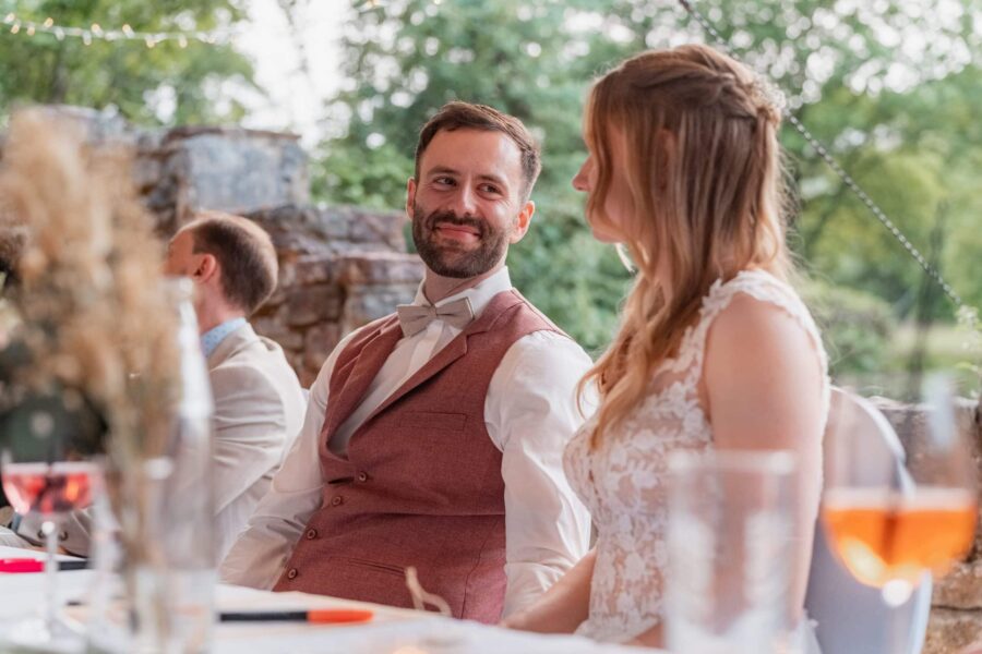 Brautpaar sitzt am festlichen Tisch im Garten.