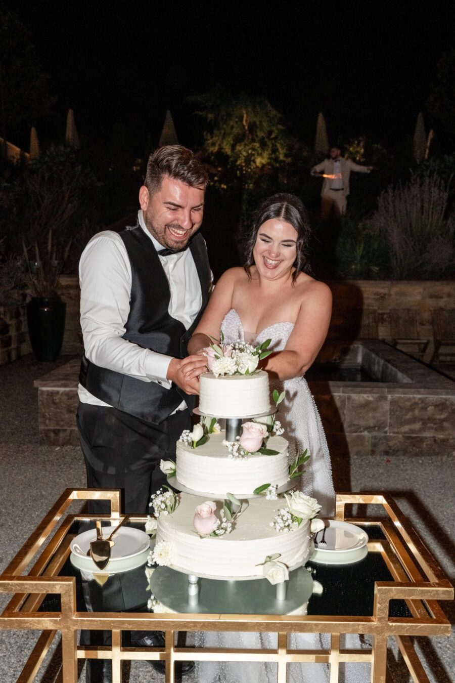 Brautpaar schneidet Hochzeitstorte im Freien an