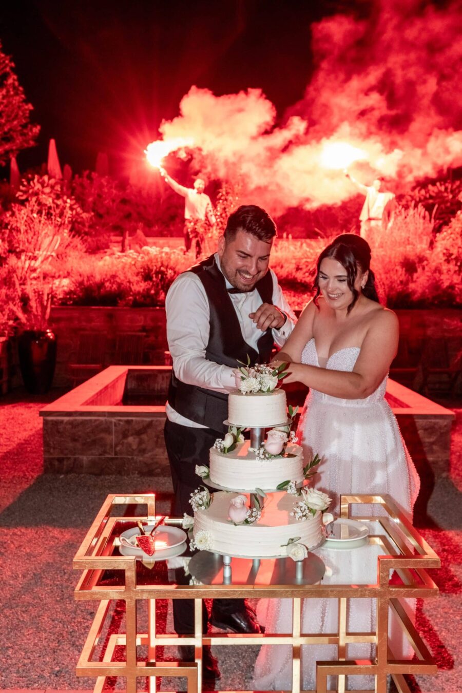 Brautpaar schneidet Hochzeitstorte an, rotes Feuerwerk