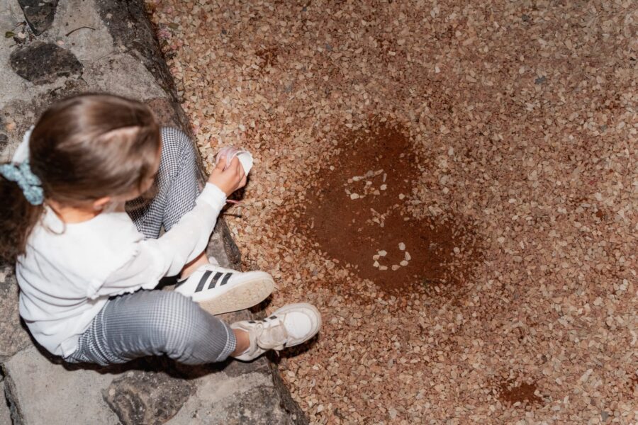 Kind sitzt auf Steinmauer und isst Eis.