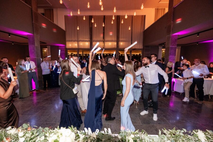 Hochzeitstanz mit Gästen und leuchtenden Stäben