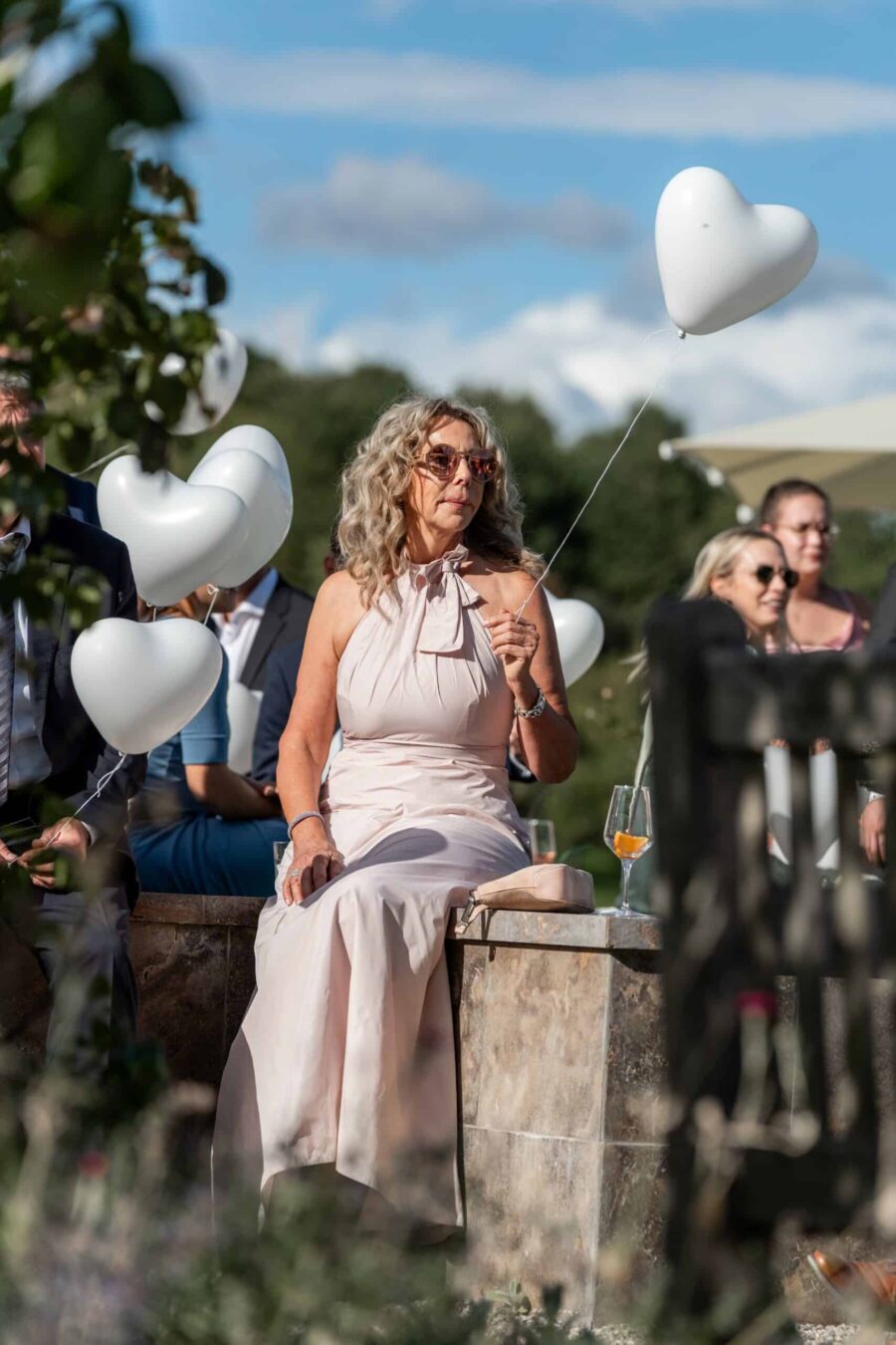Gäste mit Herz-Ballons im Garten bei Sonnenuntergang