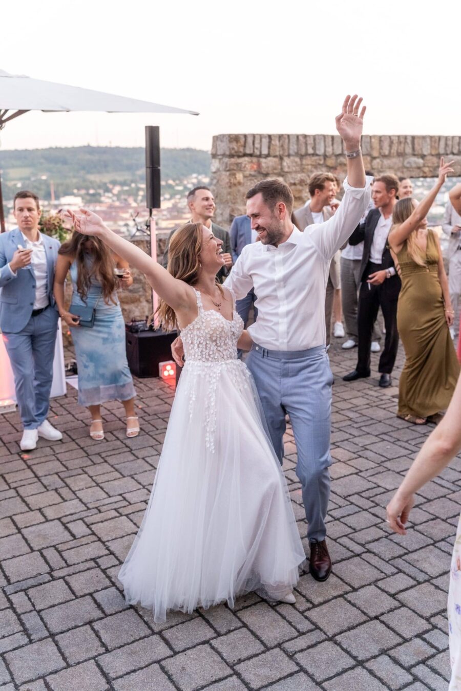 Brautpaar tanzt ausgelassen mit Gästen im Freien
