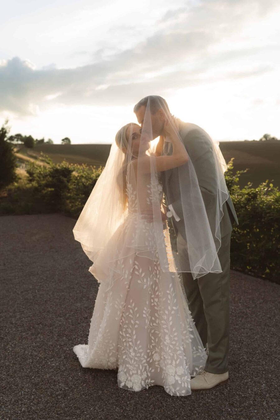 Brautpaar küsst sich im Abendlicht unter Schleier