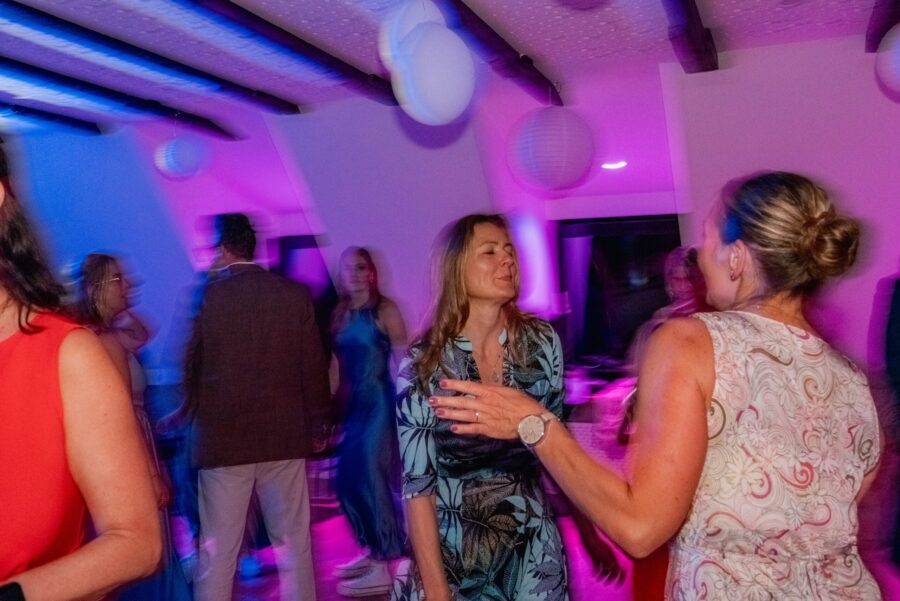 Hochzeitsfeier mit tanzenden Gästen bei bunter Beleuchtung