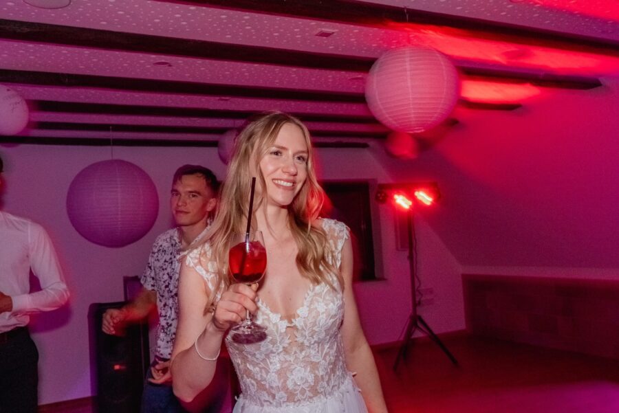 Braut im Festsaal mit Cocktailglas und Partystimmung