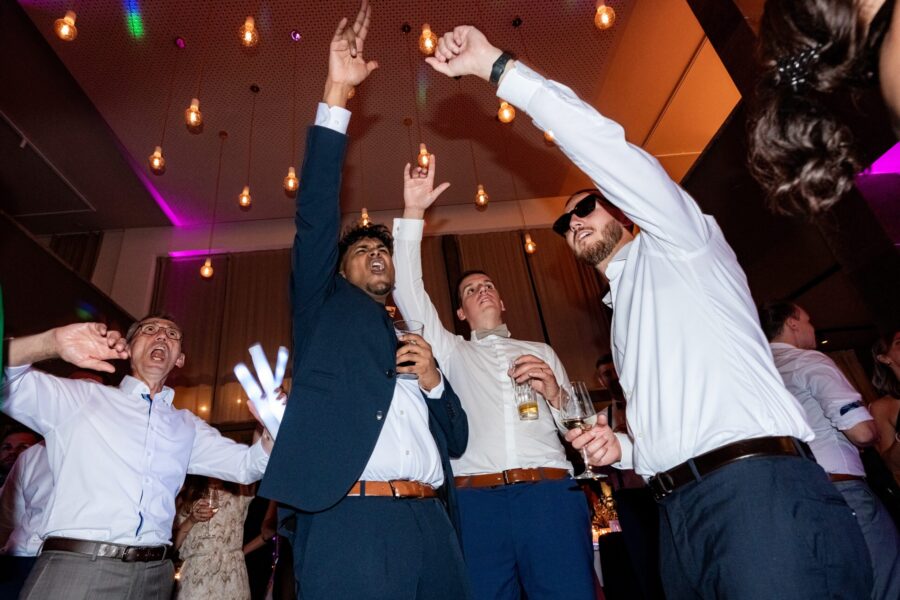 Hochzeitsgäste tanzen ausgelassen unter Lichterketten