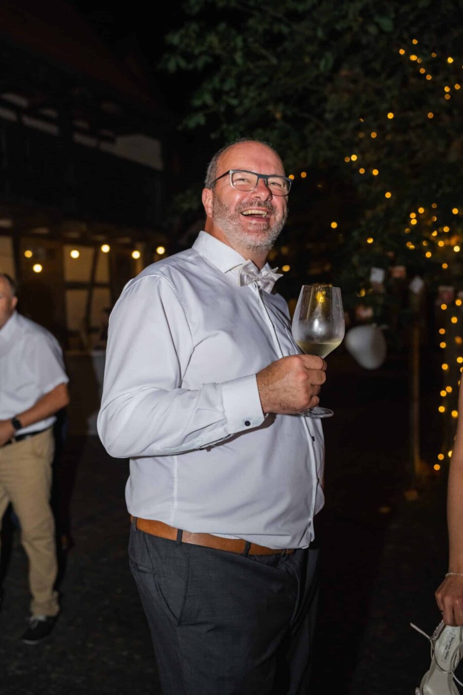 Hochzeitsgast mit Weinglas bei Abendbeleuchtung