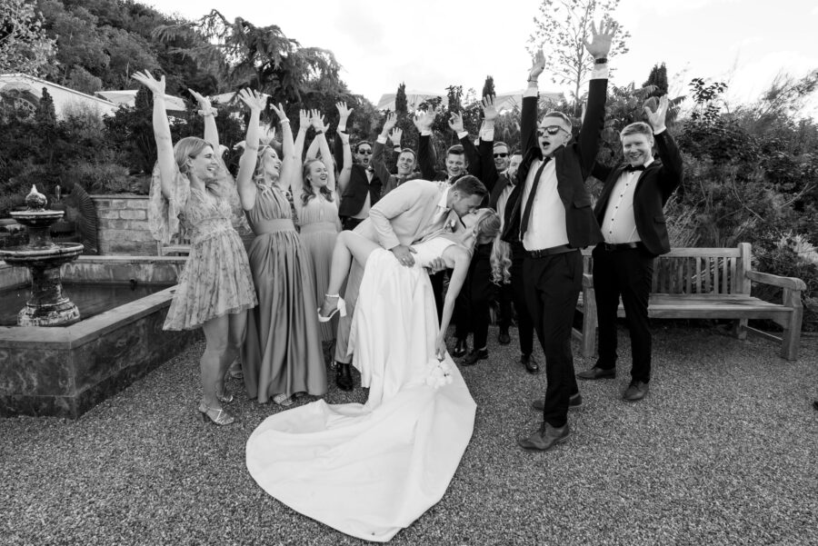 Brautpaar küsst sich umgeben von jubelnden Gästen