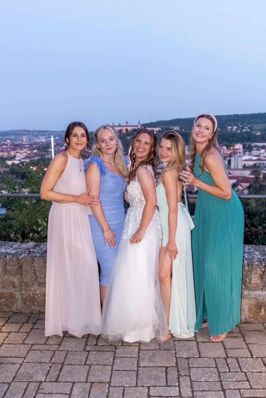 Gruppe von Frauen in Abendkleidern auf Terrasse bei Dämmerung