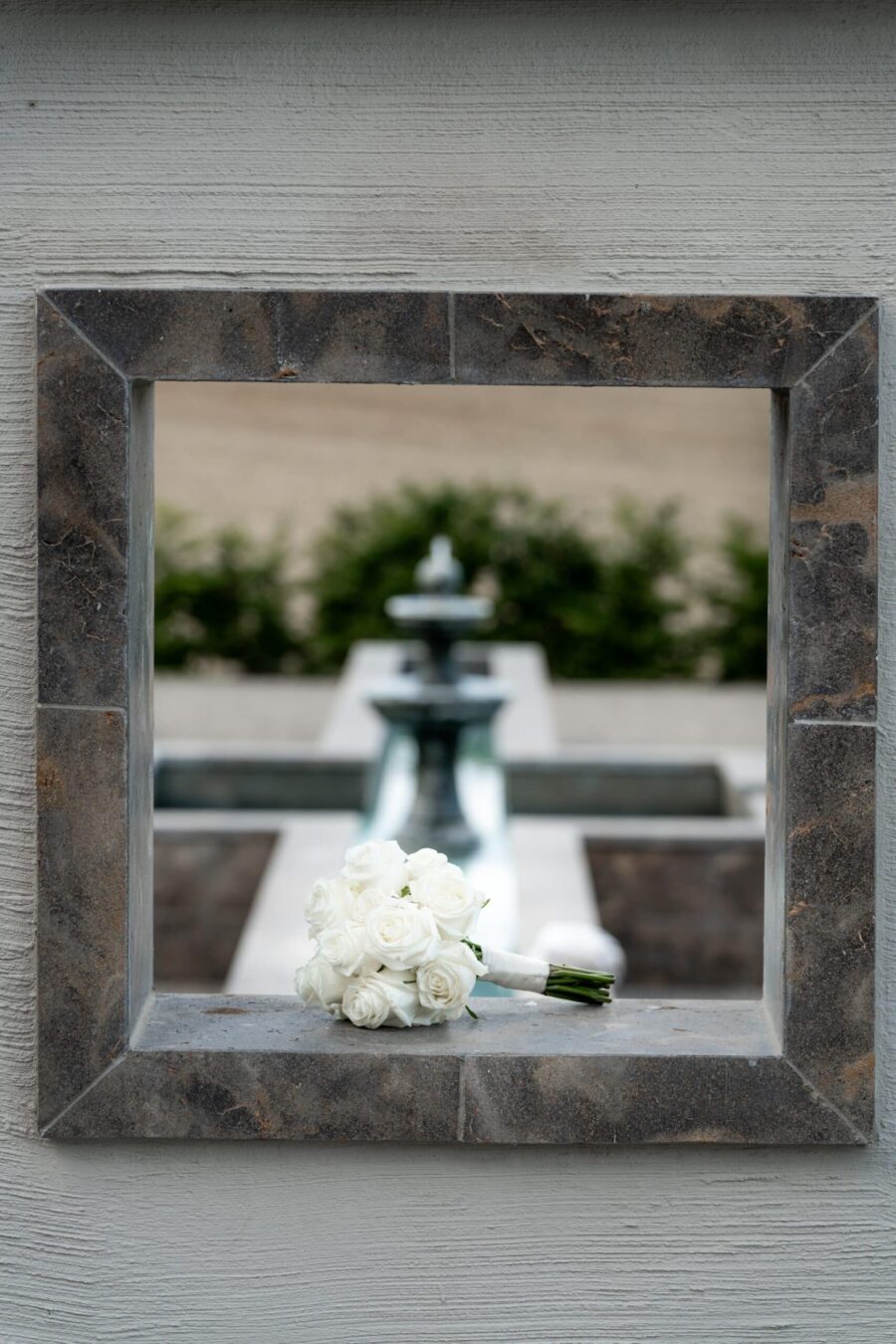 Weiße Rosen auf Fensterbank vor Brunnen.