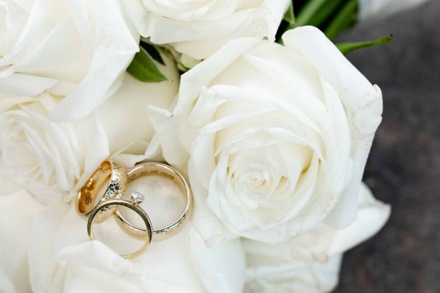 Goldene Trauringe auf weißen Rosen