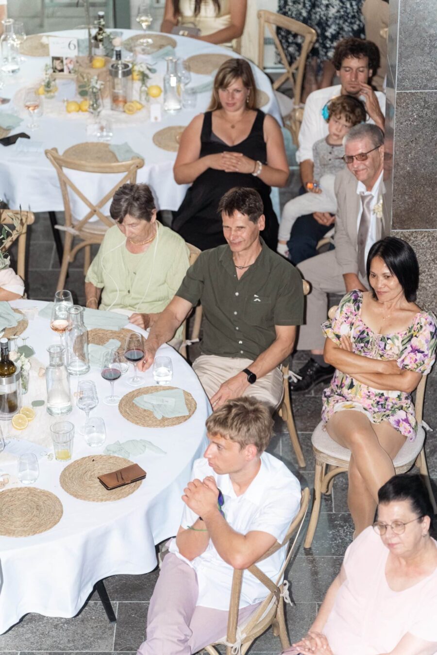 Gäste sitzen an runden Tischen bei Hochzeitsempfang.