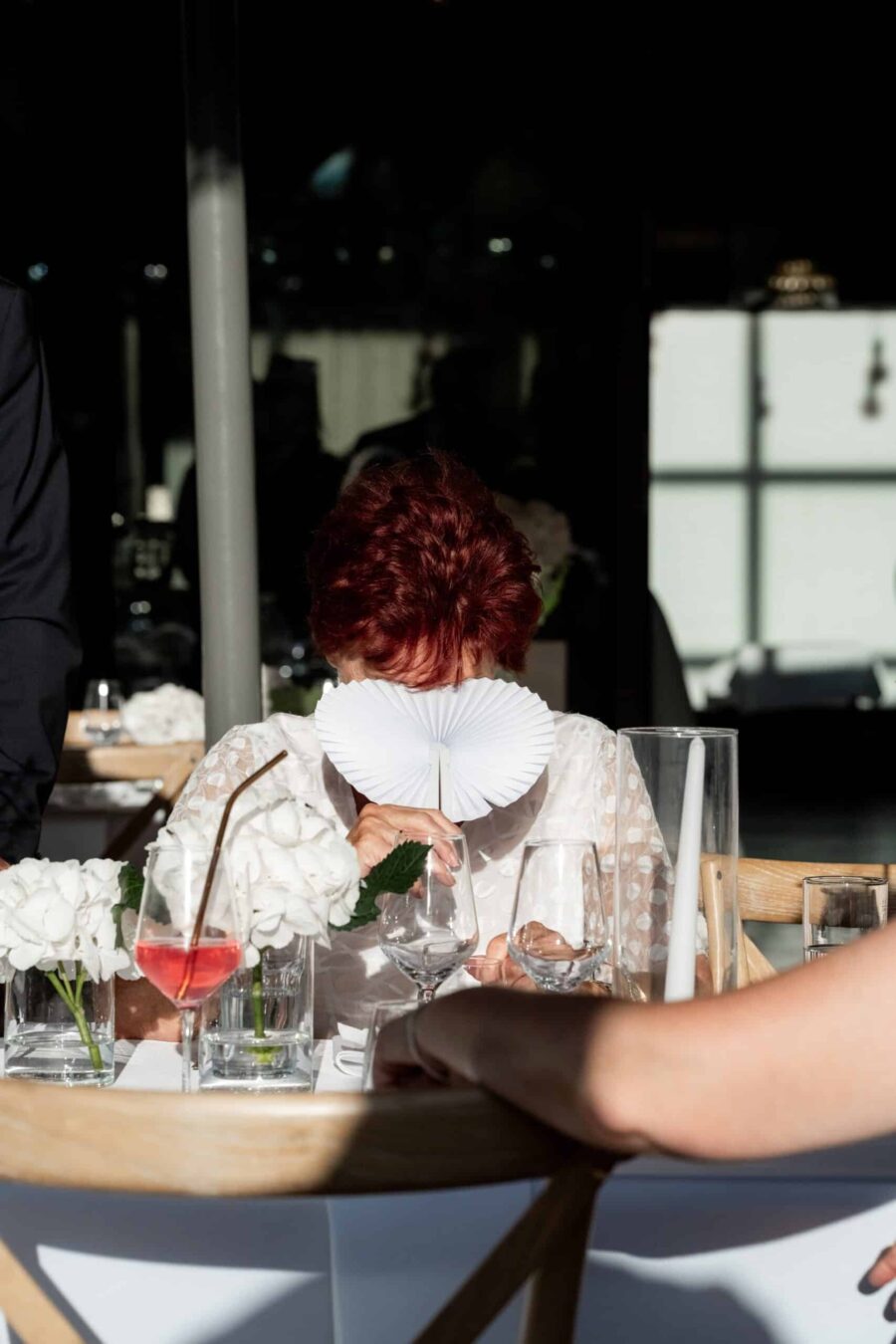 Hochzeitsgast am Tisch mit Fächer und Getränken