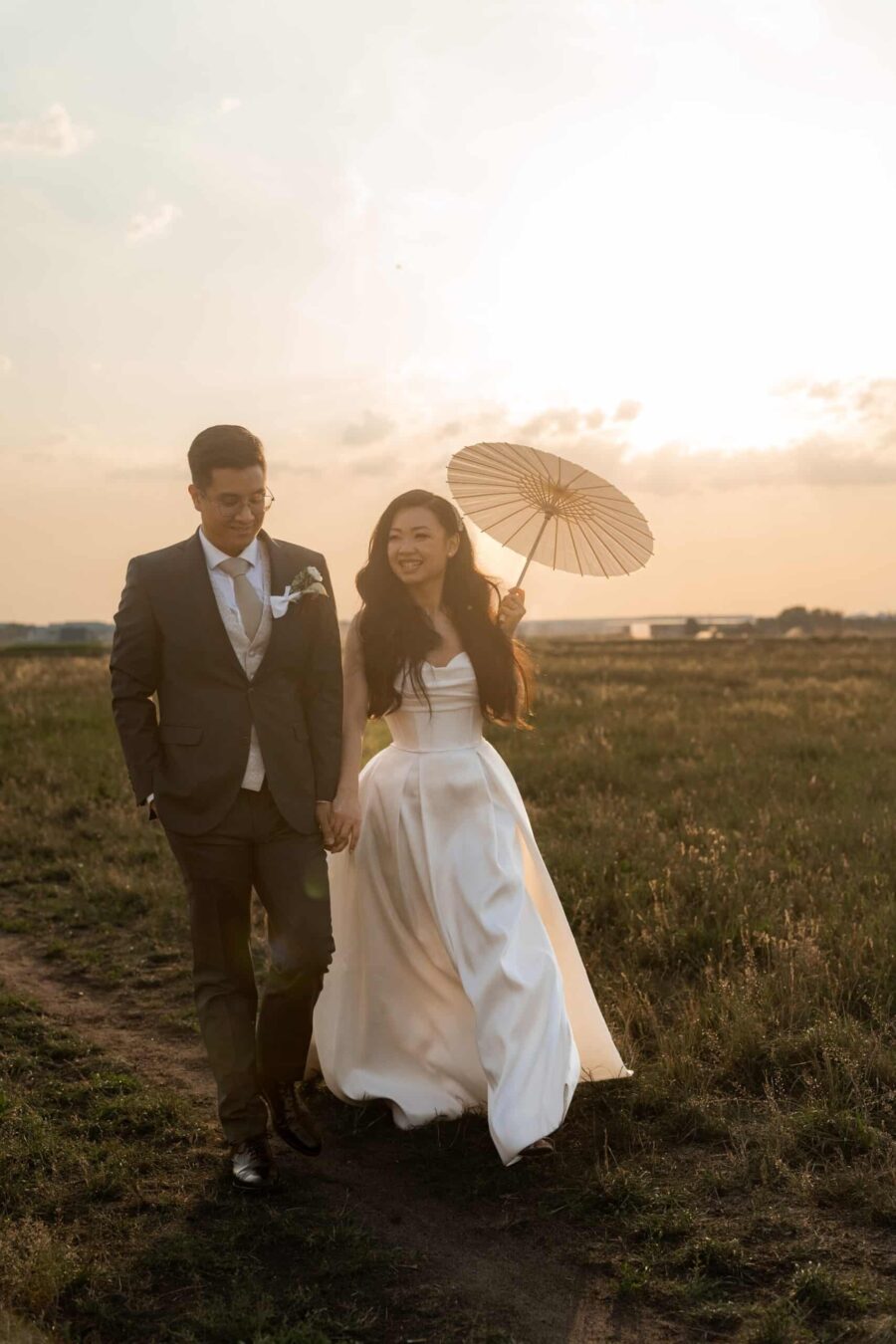 Brautpaar mit Sonnenschirm bei Sonnenuntergang