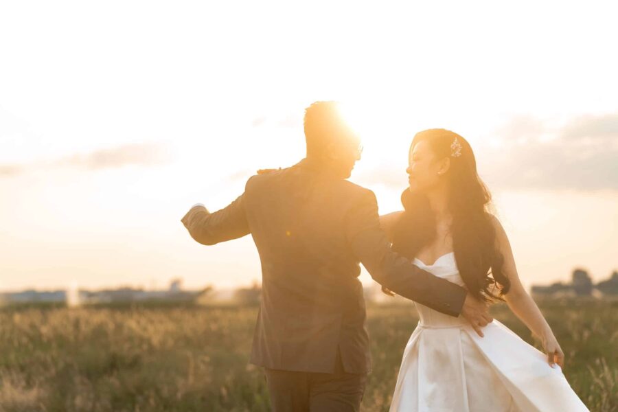 Brautpaar tanzt bei Sonnenuntergang im Feld