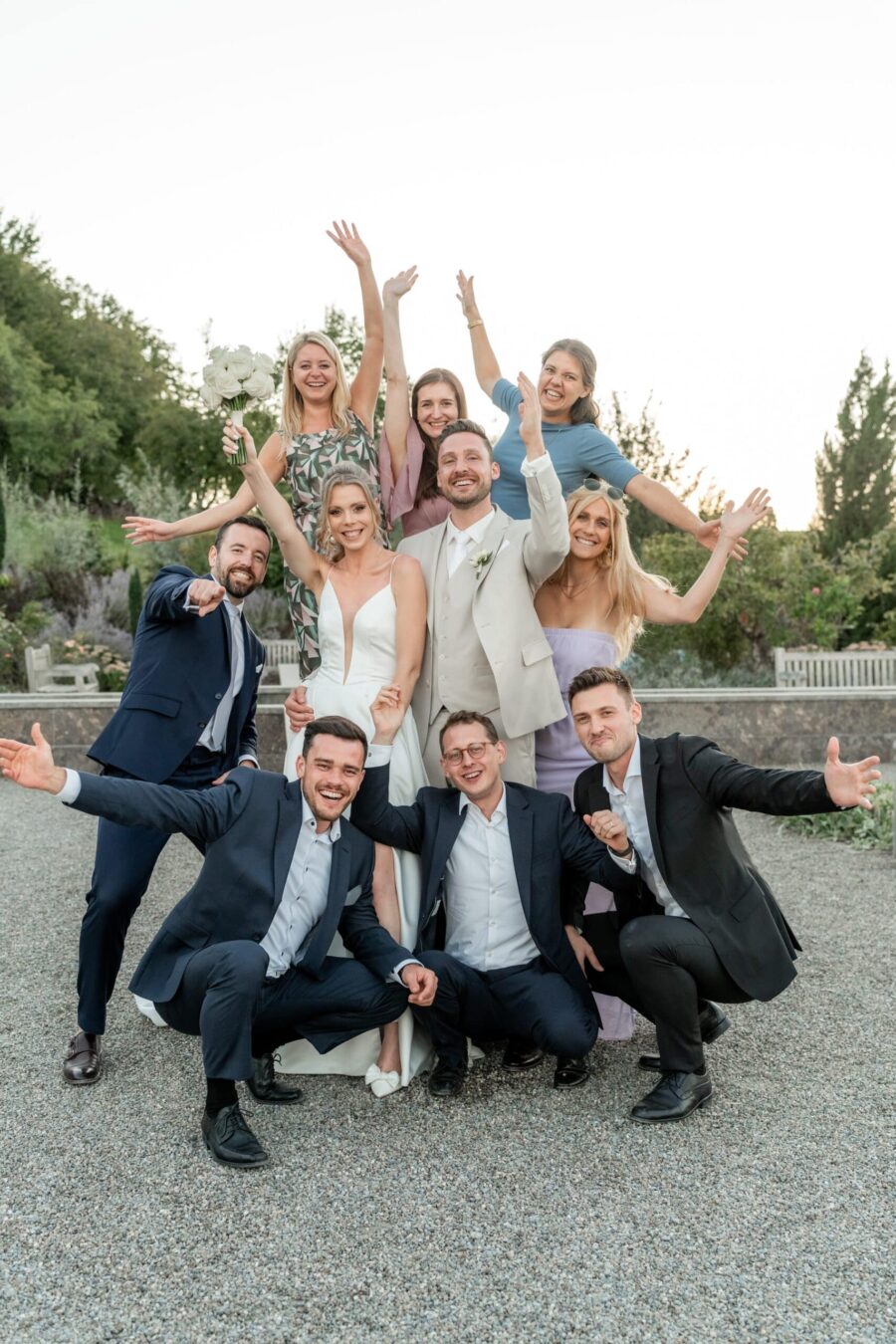 Gruppe von Hochzeitsgästen im Garten feiert zusammen.