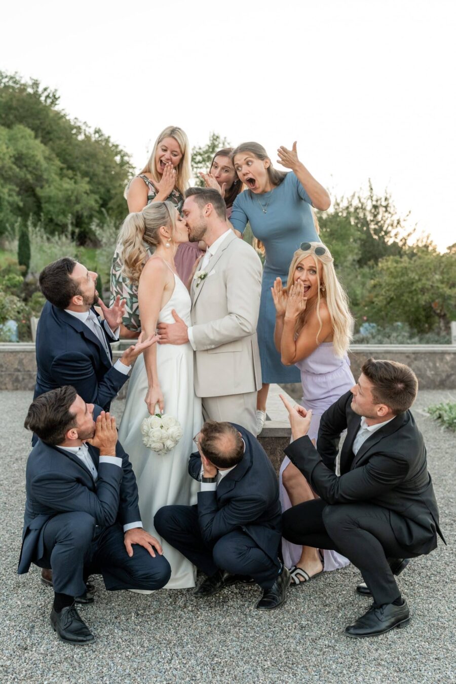 Brautpaar küsst sich, umgeben von lachenden Gästen.