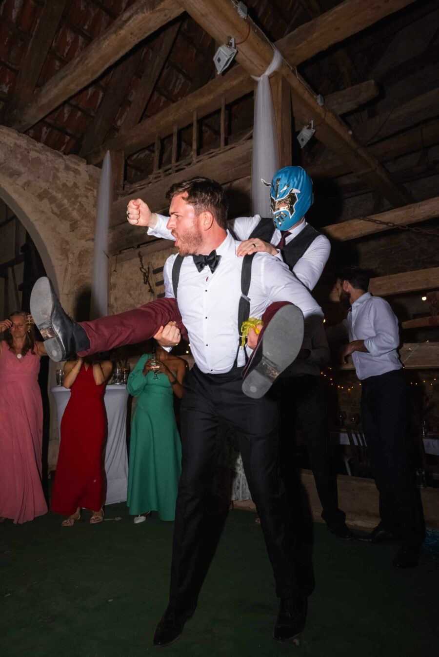 Hochzeitsgäste tanzen ausgelassen im rustikalen Saal.