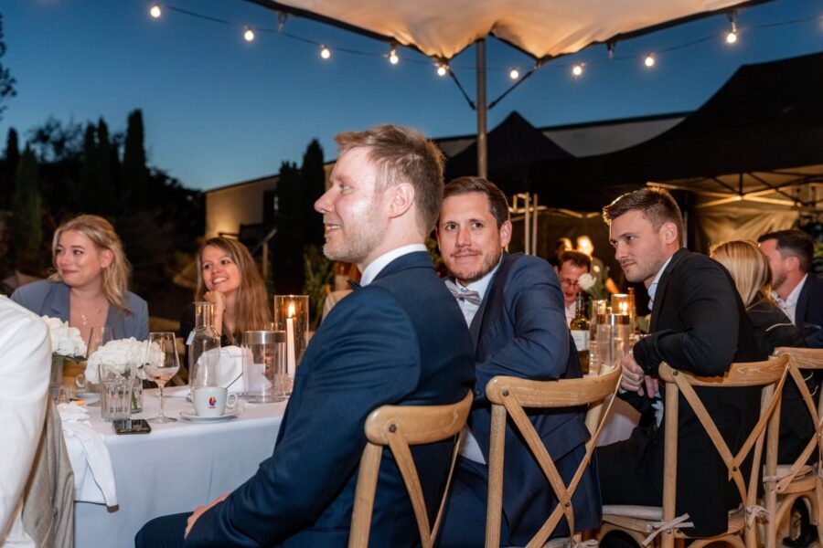 Gäste an festlich gedecktem Tisch bei Abendhochzeit