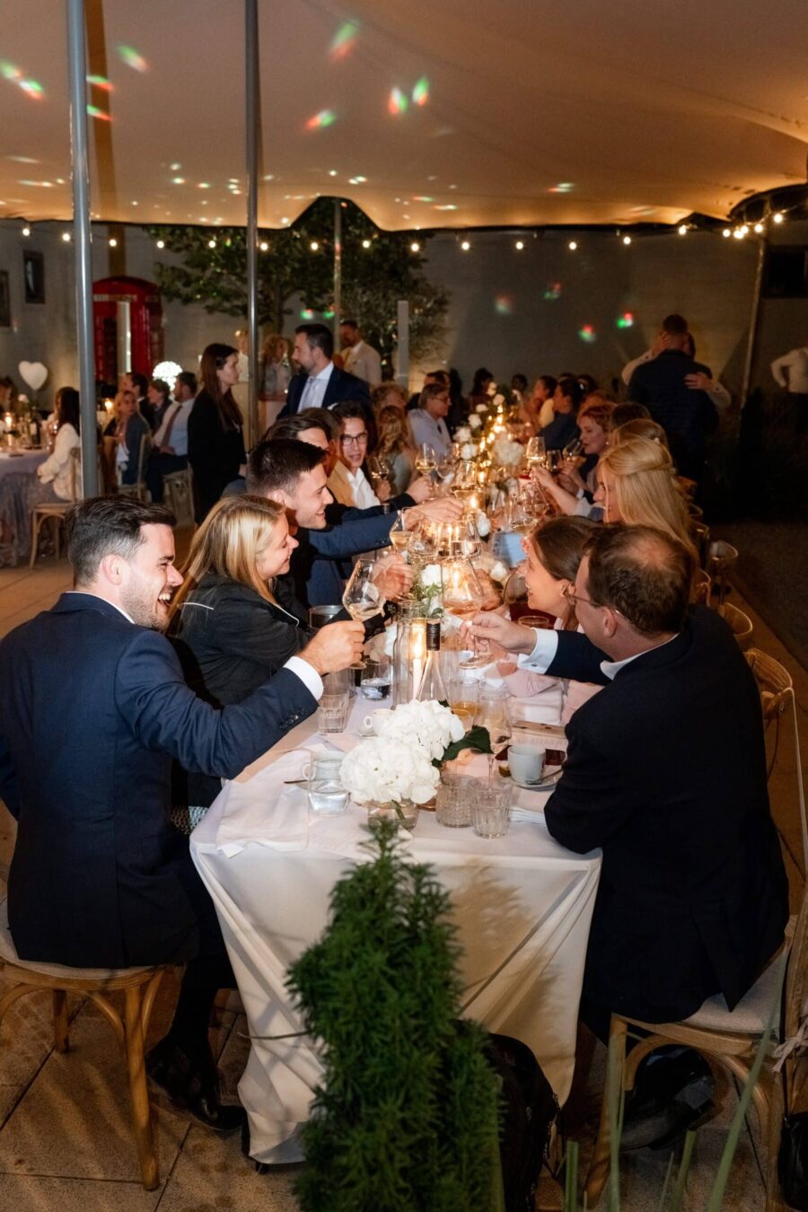 Gäste sitzen an festlicher Hochzeitstafel draußen.
