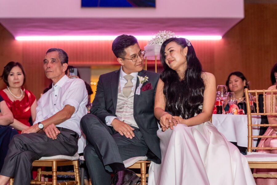 Brautpaar sitzt lächelnd bei Hochzeitsempfang