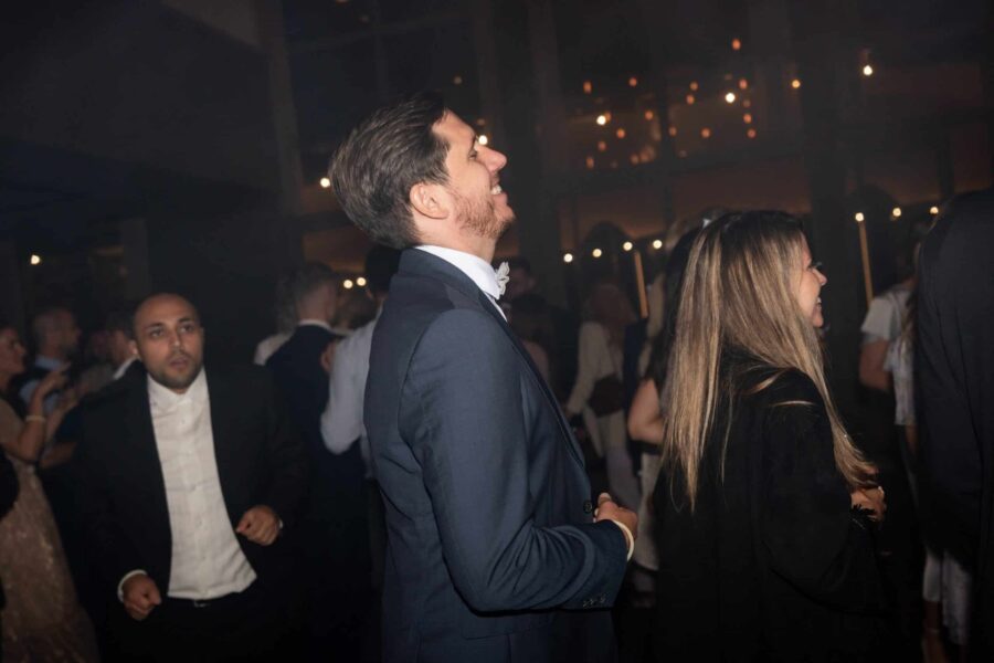 Hochzeitsgäste tanzen im festlich beleuchteten Saal.