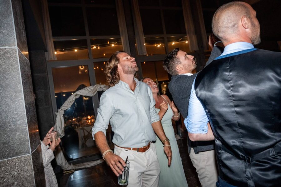 Gäste tanzen bei Hochzeitsfeier in beleuchtetem Saal