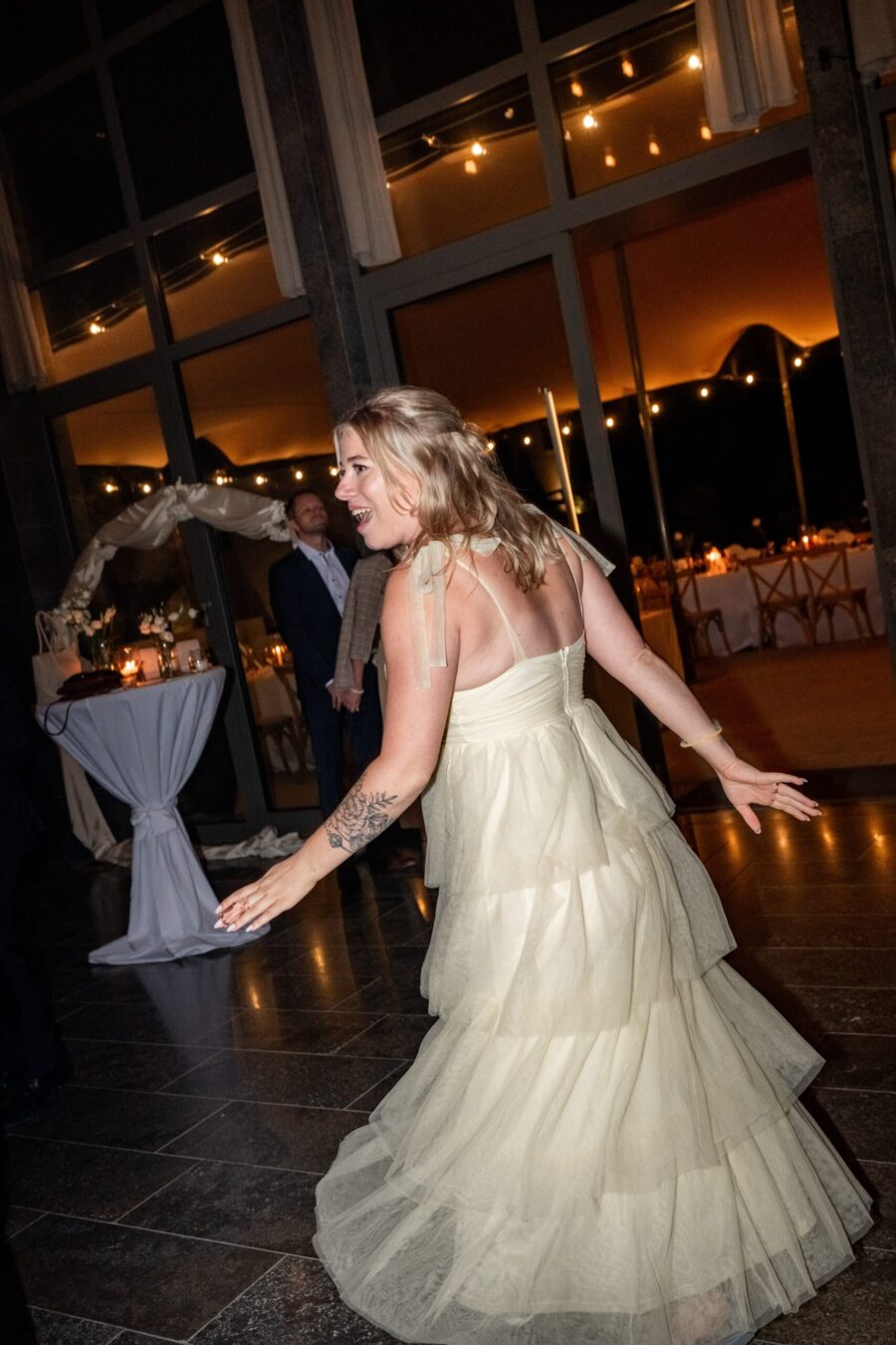 Tanzende Frau in Hochzeitslocation mit Lichtern.