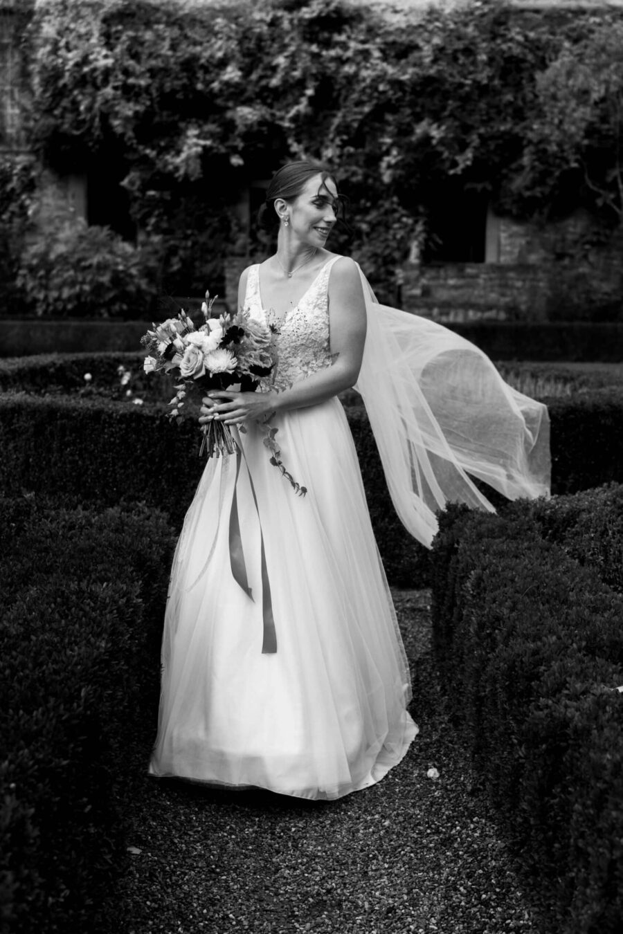 Braut mit Blumenstrauß im Garten.