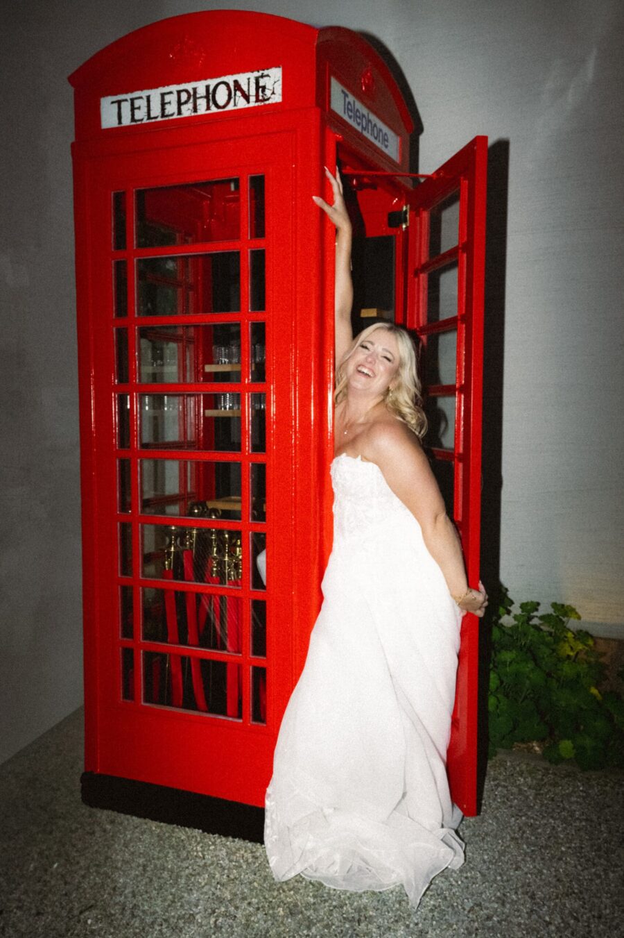 Braut in weißem Kleid neben roter Telefonzelle Villa Oriental