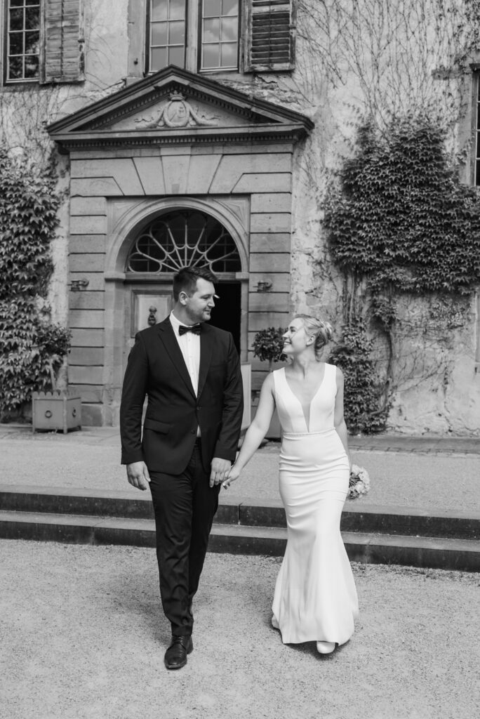 Brautpaar Hand in Hand vor historischer Villa mit Efeu